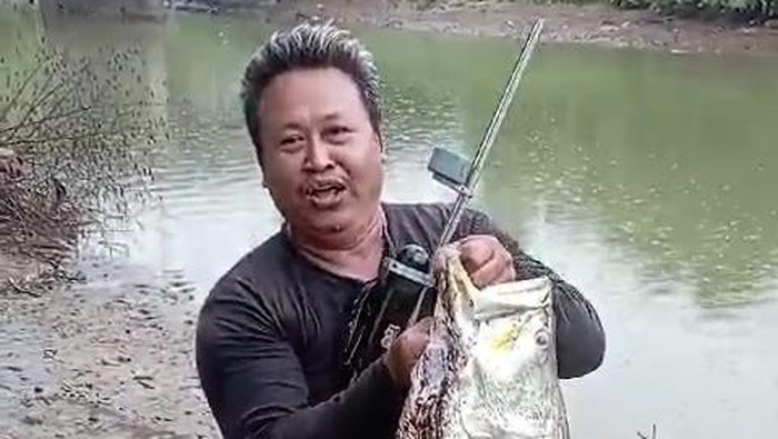 Pemancing menangkap ikan berukuran besar dari bawah jembatan Sungai Tayu, Pati, Rabu (3/1/2024).