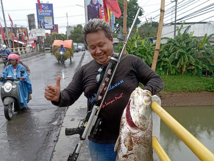 Pemancing menangkap ikan berukuran besar dari bawah jembatan Sungai Tayu, Pati, Rabu (3/1/2024).