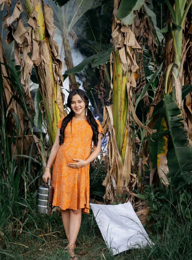 Aura pregnancy glow terpancar dari wajah Bella Bonita. Wanita berusia 25 tahun ini tampak berpose dengan latar belakang pohon pisang. Foto: Instagram/@bellabonita_r.a