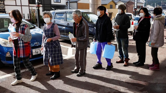 Evacuees stand in a line to receive water from a water tank car at an evacuation center, in the aftermath of an earthquake, in Wajima, Ishikawa Prefecture, Japan, January 4, 2024. REUTERS/Kim Kyung-Hoon