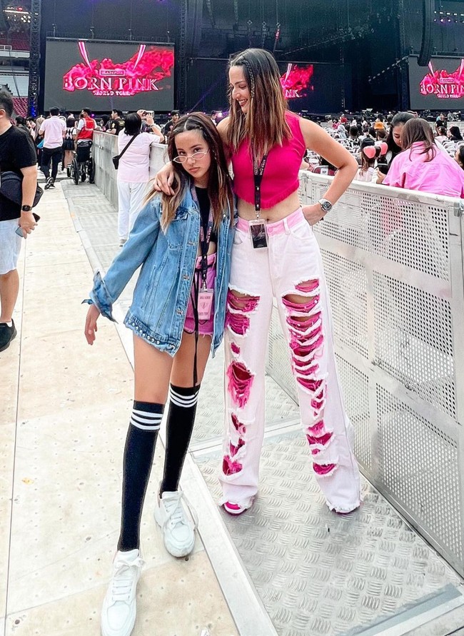 Turut menghadiri konser BLACKPINK, gaya ibu dan anak yang satu ini memang terlihat stylish. Mikha tampak memadukan jaket jeansnya dengan crop top hitam dan celana pendek merah muda. Gayanya semakin terlihat keren dengan kaos kaki selutut berwarna hitam dan sepasang sneakers putih. Foto: Instagram/@ramadhaniabakrie