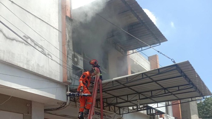 Petugas berusaha memadamkan ruko terbakar di Surabaya