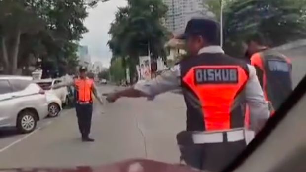 Petugas Dishub DKI ditabrak pemobil hingga dia terpaksa melompat dan menemplok di kap mobil. Pemobil acungkan jari tengah sebelum peristiwa itu terjadi. (Screenshot video viral)