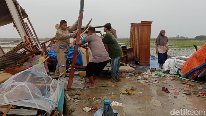 Polisi membatu warga mengevakuasi barang perabotan rumah yang tertimpa reruntuhan material bangunan.
