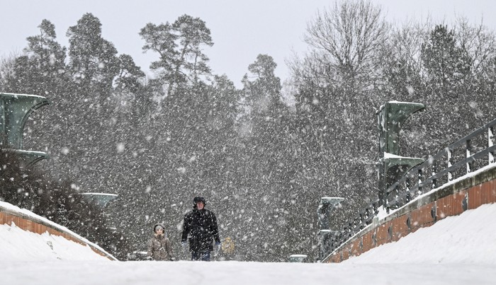 People walk during a snow fall in Stockholm, Tuesday, Jan. 2, 2023. Snow and slippery conditions continue to cause problems in many parts of Sweden. (Anders Wiklund/TT News Agency via AP)