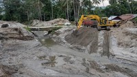 Operator alat berat mengangkat material tanah dan pasir ke truk pada proyek pembuatan saluran pengendali banjir bandang di Desa Rogo, Sigi Sulawesi Tengah, Jumat (5/1/2024).