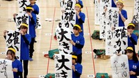 Para peserta menunjukkan karya kaligrafi tradisional Jepang mereka selama kontes kaligrafi tahun baru tahunan di aula seni bela diri Budokan.