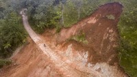 Pengendara melintasi jalan yang tertimbun material longsor di Pungut Tengah, Kerinci, Jambi, Jumat (5/1/2024).
