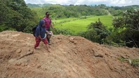 Warga melintasi jalan penghubung Kecamatan Siulak Mukai dengan Air Hangat Timur yang tertimbun material longsor.