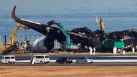 Petugas mengeluarkan puing-puing pesawat Airbus A350 Japan Airlines (JAL) yang terbakar setelah bertabrakan dengan pesawat Penjaga Pantai Jepang di Bandara Internasional Haneda di Tokyo, Jepang, Jumat (5/1/2024).