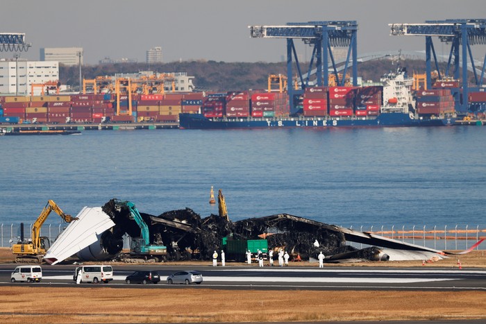 Officials remove the wreckage of a burnt Japan Airlines (JAL) Airbus A350 plane after a collision with a Japan Coast Guard aircraft at Haneda International Airport in Tokyo, Japan January 5, 2024. REUTERS/Issei Kato