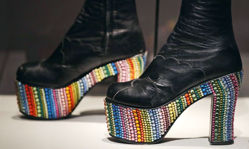 In this Tuesday, Nov. 15, 2016 photo, Elton John's rainbow glass embossed platform boots, designed by Bill Whitten in the 1970's, are displayed at the Peabody Essex Museum in Salem, Mass. From flats to stilettos, what we put on our feet says something about who we are. That's the premise of new exhibition in Massachusetts. 