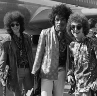 Perubahan juga ditandai dengan euforia budaya pop yang melahirkan tren glamrock yang flamboyan. Sejumlah musisi mempelopori gaya tersebut di antaranya pemain bas Noel Redding, gitaris Jimi Hendrix, dan drummer Mitch Mitchell, seperti yang terlihat ketika mereka dipotret di Bandara Heathrow, London, Inggris, pada 1967. (Foto: AP/Peter Kemp)