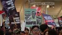 Sejumlah pendukung Capres-cawapres nomor urut tiga Ganjar Pranowo dan Mahfud MD memegang poster dukungan di depan gedung lokasi debat ketiga Pilpres 2024 di Istora Senayan, Jakarta, Minggu (7/1/2024).