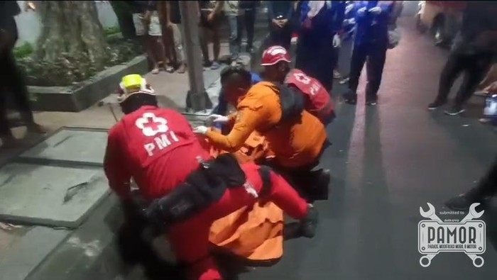 Petugas saat mengevakuasi jasad pria tanpa identitas yang tewas usai menabrak lampu jalan di Surabaya