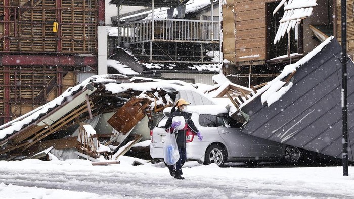 CORRECTS DATE - Firefighters search for missing people in the snow-covered marketplace which was burnt out by a large fire caused the earthquakes, in Wajima, Ishikawa prefecture, Monday, Jan. 8, 2024. Rescue teams worked through snow to deliver supplies to isolated hamlets Monday, a week after a powerful earthquake hit western Japan. (Kyodo News via AP)