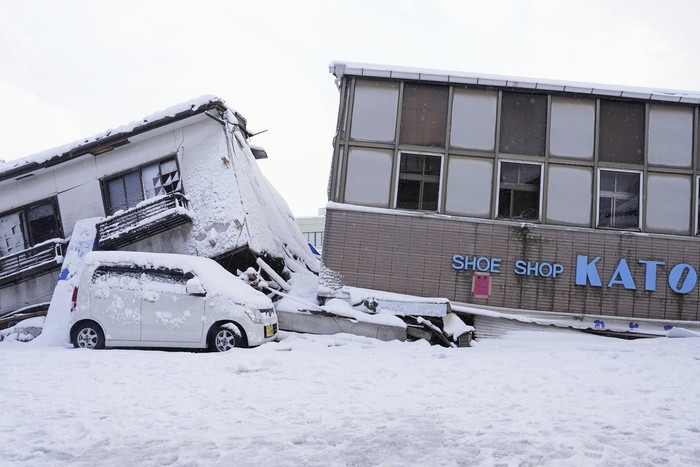 CORRECTS DATE - Firefighters search for missing people in the snow-covered marketplace which was burnt out by a large fire caused the earthquakes, in Wajima, Ishikawa prefecture, Monday, Jan. 8, 2024. Rescue teams worked through snow to deliver supplies to isolated hamlets Monday, a week after a powerful earthquake hit western Japan. (Kyodo News via AP)