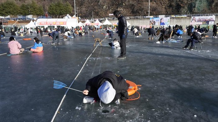 Potret Antusias Warga Korsel Lomba Mancing Ikan di Sungai Beku Participants cast lines through holes drilled in the surface of a frozen river during a trout catching contest in Hwacheon, South Korea, Saturday, Jan. 6, 2024. The contest is part of an annual ice festival which draws over one million visitors every year. (AP Photo/Ahn Young-joon)