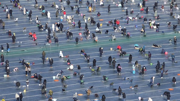 Participants cast lines through holes drilled in the surface of a frozen river during a trout catching contest in Hwacheon, South Korea, Saturday, Jan. 6, 2024. The contest is part of an annual ice festival which draws over one million visitors every year. (AP Photo/Ahn Young-joon)