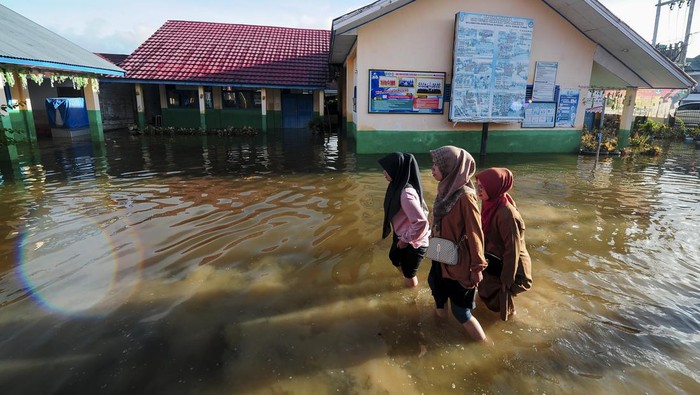 Sekolah masih diliburkan akibat banjir di Sungai Penuh Siswa menerobos genangan banjir luapan Sungai Batang Merao yang merendam SDN 032 di Simpang Tiga Rawang, Sungai Penuh, Jambi, Senin (8/1/2024). Banjir yang terjadi sejak Minggu (31/12/2023) atau memasuki hari ke-9 itu masih menggenangi sekolah, akibatnya sebanyak 109 siswa yang mayoritas rumahnya juga terdampak banjir masih diliburkan, sementara beberapa peralatan elektronik, perangkat ujian siswa dan arsip sekolah rusak. ANTARA FOTO/Wahdi Septiawan/aww.