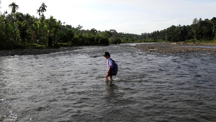 Seorang murid SDN 36 menyeberangi Sungai Batang Duku untuk menuju sekolah di Korong (dusun) Padang Galo, Kabupaten Padang Pariaman, Sumatera Barat, Senin (8/1/2024). Warga Korong Padang Galo meminta pemerintah setempat untuk membangun akses jembatan agar memudahkan anak-anak bersekolah dan mobilitas masyarakat mengangkut hasil bumi atau pertanian. ANTARA FOTO/Muhammad Arif Pribadi/aww.