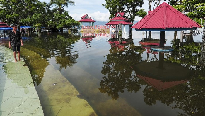 Warga berjalan di depan tokonya yang terendam luapan air Danau Kerinci di Sanggaran Agung, Kerinci, Jambi, Selasa (9/1/2024). Tingginya intensitas hujan di wilayah hulu sejak dua pekan terakhir mengakibatkan air Danau Kerinci meluap dan merendam kawasan pertokoan dan rumah jaga di sekitar danau, sementara hingga Selasa (9/1/2024) sejumlah kawasan permukiman di Kabupaten Kerinci dan Kota Sungai Penuh juga terpantau terendam. ANTARA FOTO/Wahdi Septiawan/tom.