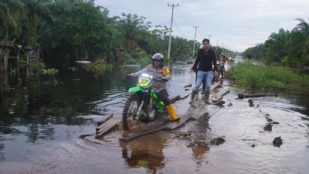 Kapolres Bengkalis, AKBP Setyo Bimo Anggoro menerobos banjir dengan mengendarai motor trail hijau untuk cek lokasi TPS rawan banjir. (Dok. Polres Bengkalis)