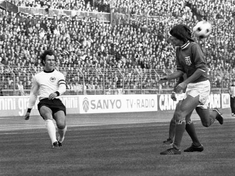 Pemain sepak bola Jerman dan kapten tim Franz Beckenbauer, kiri, menembak melewati pemain sepak bola Yunani yang tidak dikenal saat pertandingan Jerman Barat vs Yunani pada 11 November 1975 di Dusseldorf, Jerman. (AP Photo/Klaus Schlagmann)