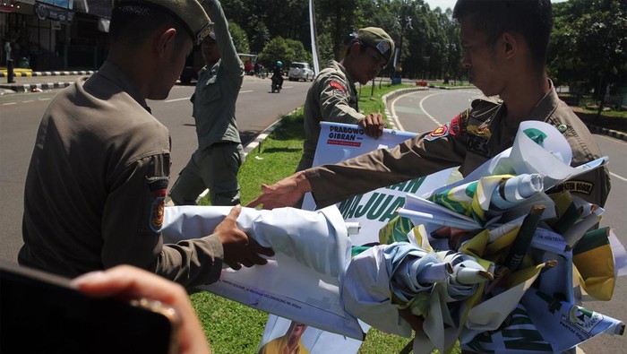Petugas gabungan dari Bawaslu dan Satpol PP mencopot alat peraga kampanye (APK) di jalan lingkar Stadion Pakansari, Kabupaten Bogor, Jawa Barat, Selasa (9/1/2024). Penertiban APK tersebut dilakukan karena pemasangannya tidak sesuai peraturan KPU dan melanggar aturan Pemilu 2024. ANTARA FOTO/Yulius Satria Wijaya/tom.
