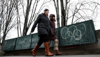 Orang-orang melewati kios-kios buku yang disebut bouquinistes di sepanjang tepi Sungai Seine di Paris, Prancis, Senin (8/1/2024).
