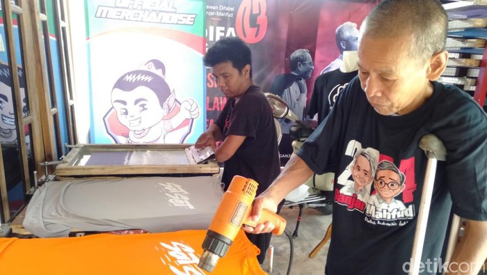 Divisi Merchandise DIFAGAMA, Bejo Riyanto saat menyablon kaus warga yang mengantre sablonase.