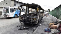 Orang-orang berjalan melewati sisa-sisa bus yang terbakar setelah Presiden Ekuador Daniel Noboa mengumumkan keadaan darurat selama 60 hari menyusul hilangnya Adolfo Macias dari penjara. 