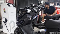 Pengendara mengisi ulang daya baterai pada sepeda motor listrik di dealer Polytron, Jl Arteri Pondok Indah, Jakarta Selatan, Rabu (10/1/2024).