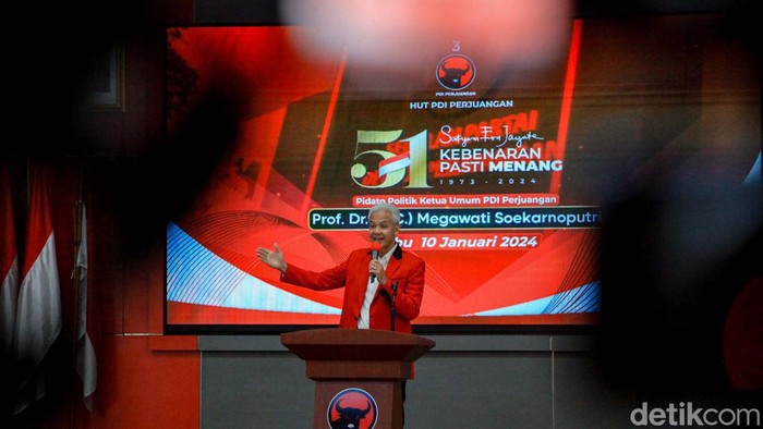 Capres Ganjar Pranowo berpidato di acara HUT PDIP. Ganjar memakai jas merah berbicara di hadapan undangan.