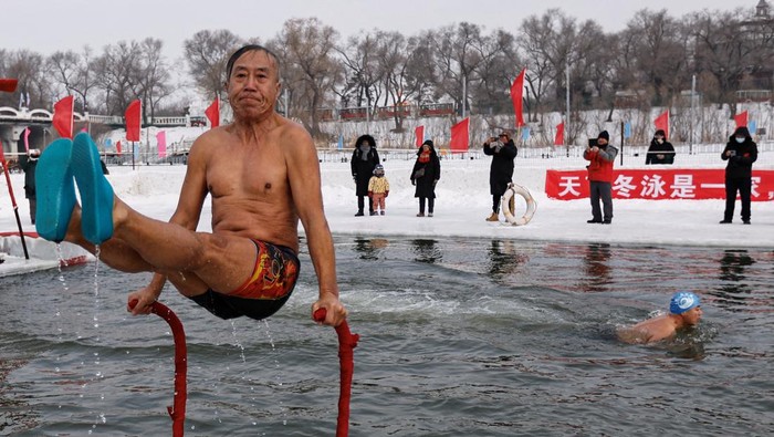 A winter swimmer shows off his skills after diving into a frozen Songhua river, during a winter swimming event at the International Ice and Snow Festival, in Harbin, Heilongjiang province, China January 6, 2024. REUTERS/Tingshu Wang