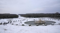 Orang-orang berjalan-jalan di gang-gang taman yang tertutup salju di Chateau de Versailles. Suhu turun di bawah nol derajat Celsius (32 derajat Fahrenheit).