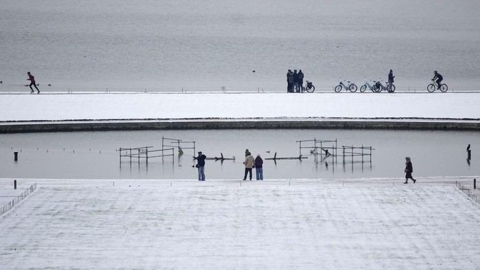 People stroll in the alleys of the snow-covered gardens of the Chateau de Versailles Tuesday, Jan. 9, 2024 in Versailles, west of Paris, where temperatures fell under zero degree Celsius (32 degrees Fahrenheit). (AP Photo/Christophe Ena)