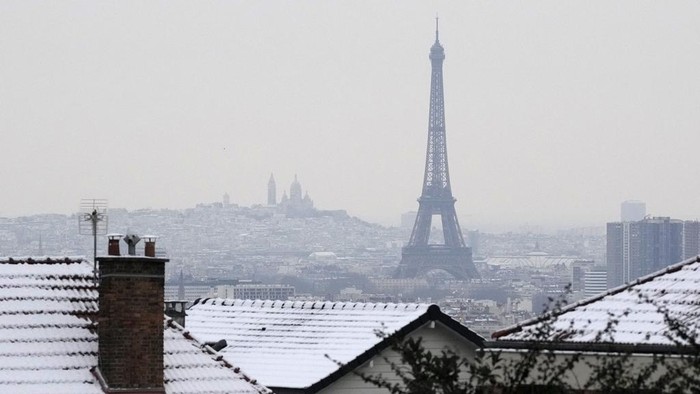 People stroll in the alleys of the snow-covered gardens of the Chateau de Versailles Tuesday, Jan. 9, 2024 in Versailles, west of Paris, where temperatures fell under zero degree Celsius (32 degrees Fahrenheit). (AP Photo/Christophe Ena)
