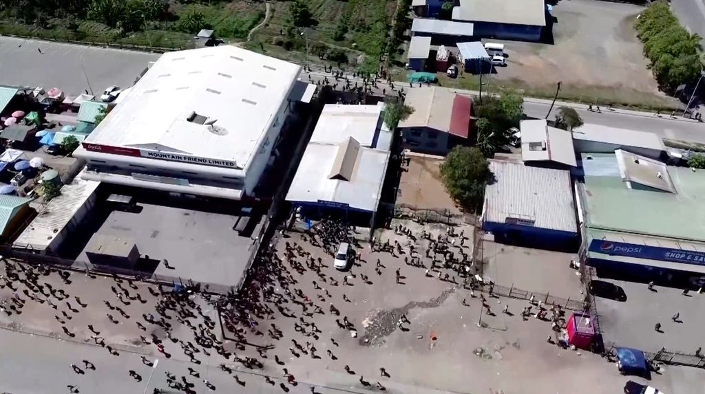 Orang-orang berkumpul di dekat sebuah gedung, di tengah laporan penjarahan dan pembakaran yang meluas ketika polisi dan sektor publik memprotes pemotongan gaji yang menurut para pejabat disebabkan oleh kesalahan administratif, di Port Moresby, Papua Nugini, 10 Januari 2024, dalam tangkapan layar yang diperoleh dari sebuah video. (Mackenzie Waide/via REUTERS)