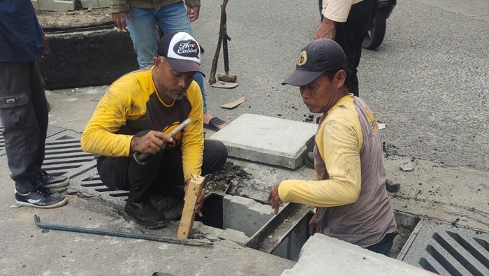 Petugas Dinas PUPR Kota Depok memperbaiki penutup gorong-gorong di Jalan GDC yang rusak.
