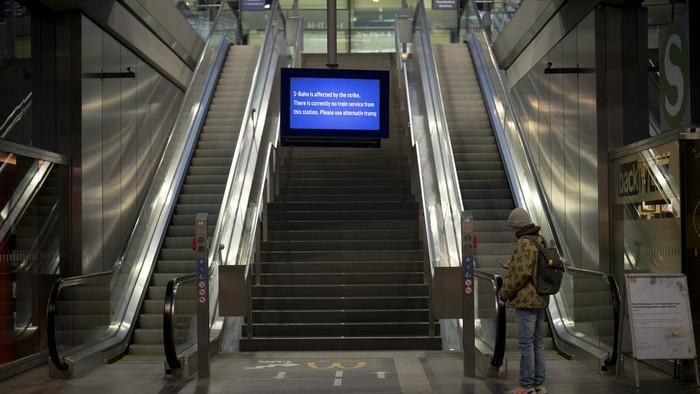 A person looks at a mobile device at the main railway station in Berlin, Germany, Wednesday, Jan. 10, 2024. A union representing many of Germany’s train drivers has started a nearly three-day strike in a rancorous dispute with the country’s state-owned main railway operator over working hours and pay. (AP Photo/Markus Schreiber)