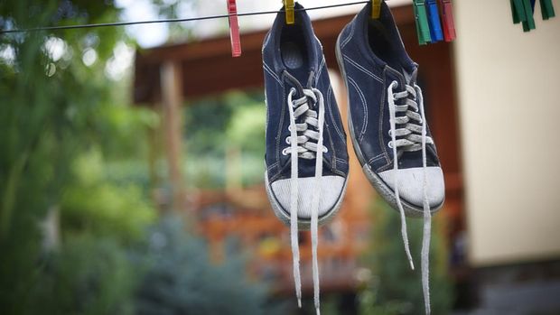 1226147905 Sneakers with foam of powder detergent water dissolution and wooden brush on cement floor. Washing dirty shoes. Top view