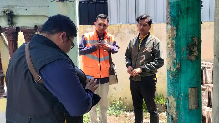 Petugas PLN melakukan survei rumah warga yang ingin pindah tiang listrik di Sidoarjo.