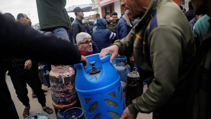 Children look on as Palestinians wait to fill their cylinders with cooking gas amid shortage, as the conflict between Israel and Hamas continues, in Rafah, in the southern Gaza Strip, January 11, 2024. REUTERS/Saleh Salem
