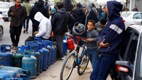 Seorang anak membawa tabung gas dengan sepeda. 