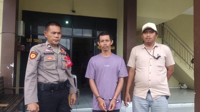 Suzanto (tengah) saat diamankan di kantor polisi.