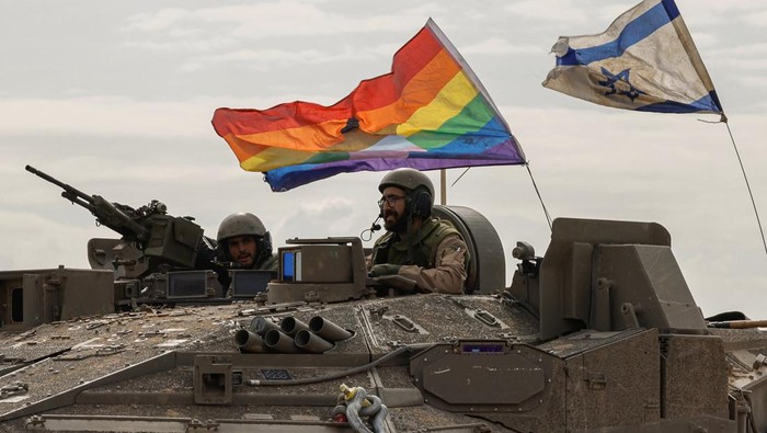 An Israeli tank with a rainbow flag with a Star of David and an Israeli national flag re-enters Israel from Gaza, amid the ongoing conflict between Israel and the Palestinian Islamist group Hamas, near the Israel-Gaza border, in southern Israel, January 11, 2024. REUTERS/Tyrone Siu