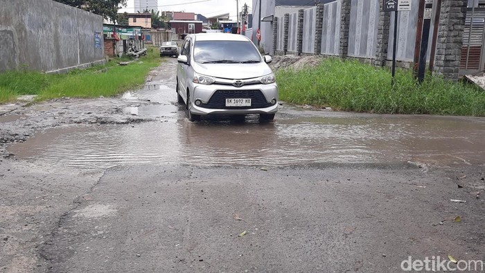 Sebuah mobil hendak melintasi lubang yang digenangi air di Jalan Danau Sentani, Kelurahan Sei Agul, Kecamatan Medan Barat, Kota Medan. (Felicia Gisela Sihite/detikSumut)