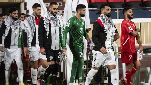 Palestinian players wearing traditional scarves enter the pitch ahead of the 2026 FIFA Soccer World Cup qualifier against Lebanon in Sharjah, United Arab Emirates, Thursday, Nov. 16, 2023. (AP Photo/Martin Dokoupil)