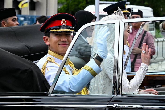 BRUNEI-ROYAL-WEDDING Prince Abdul Mateen and Yang Mulia Anisha Rosnah wave from their car during the wedding procession in Brunei's capital Bandar Seri Begawan on January 14, 2024. (Photo by MOHD RASFAN / AFP)